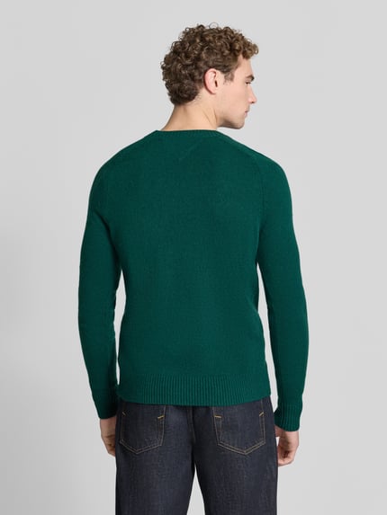 Męski model nosi Regular Fit Pullover aus Lammwoll-Mix von Tommy Hilfiger, jednokolorowy, imitacja dzianiny, matowy, faktura, detal z logo, szwy, okrągły dekolt, długi rękaw, prążkowane zakończenia, drobny splot, widok całej sylwetki od tyłu.