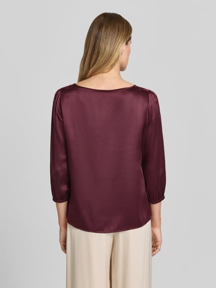 Vrouwenmodel draagt Blusenshirt aus Seide mit 3/4-Arm van Marc Cain in bordeaux, zuiver zijde, regular fit, ronde hals, ruglengte maat 36: 60 cm, mouwlengte maat 36: 49 cm. Ganzkörperansicht rugaanzicht.