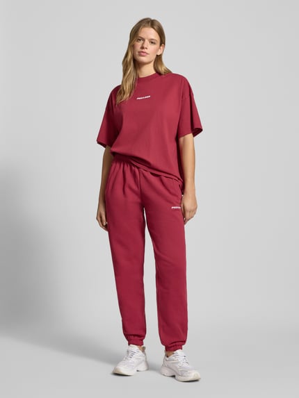 Frauenmodel trägt Oversized T-Shirt mit Logo Modell 'BRACY' von Pegador aus reiner Baumwolle in Dunkelrot, Ganzkörperansicht von vorne.