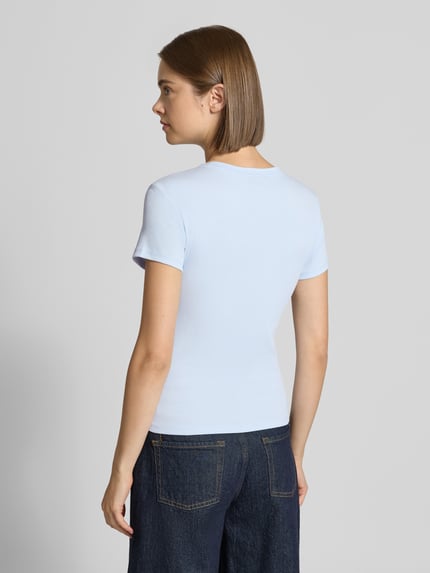 Modelka kobieca ma na sobie jasnoniebieski Slim Fit T-Shirt aus Baumwoll-Mix von Tommy Jeans, Damski t-shirt, tekstura gładka, widok całej sylwetki z tyłu.
