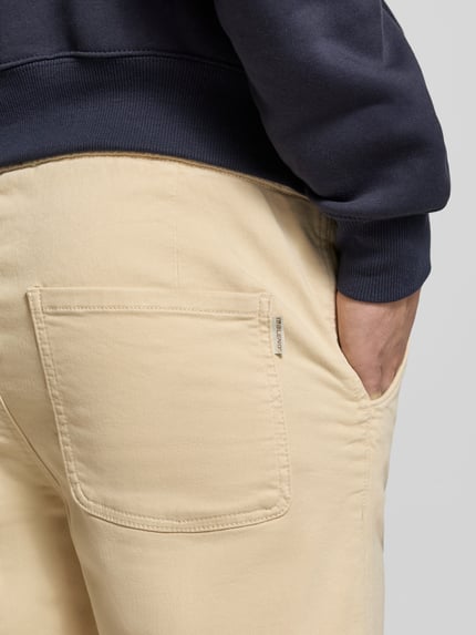 Männermodel trägt Slim Fit Stoffhose mit Eingrifftaschen Modell 'Thunder' von Blend in Beige, Rückansicht Detailaufnahme, elastischer Baumwoll-Mix, Gesäßtasche, legerer Stil.