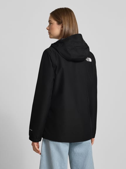 Frauenmodel trägt czarną kurtkę funkcyjną z nadrukiem z logo, krój regular fit, Model 'Quest Mono' od The North Face, Kaptur, zamek błyskawiczny, długość tyłu w rozmiarze S: 69 cm, szerokość ramion w rozmiarze S: 40 cm, szerokość w rozmiarze S: 40 cm, długość rękawów w rozmiarze S: 63 cm, matowa tekstura, prosty fason, widoczny tył, Ganzkörperansicht Rückansicht.