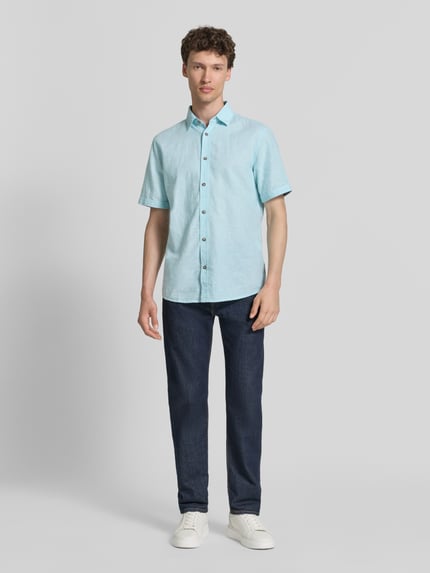 Męski model nosi Regular Fit Freizeithemd aus Leinen-Baumwolle-Mix von Tom Tailor, efekt: jednolity kolor, kołnierzyk typu kent, listwa guzikowa jednorzędowa, krótki rękaw, mieszanka lnu i bawełny, koszula casualowa; jasnoniebieski, prosta forma, gładka tekstura, Ganzkörperansicht von vorne.
