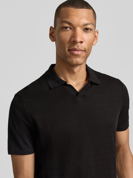 Männermodel trägt Modern Fit Poloshirt mit Polokragen und Label-Detail von MARKUP aus Reine Baumwolle in Schwarz, Nahaufnahme Oberkörper.