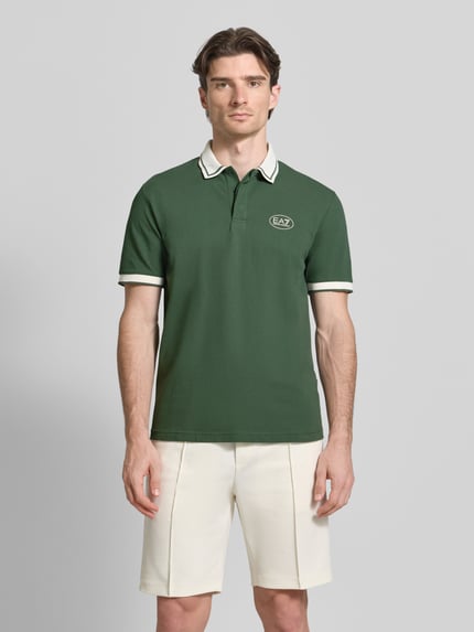 Männermodel trägt Regular Fit Poloshirt mit Logo-Print von EA7 Emporio Armani in Dunkelgrün, Kurzarm, Polokragen, Ganzkörperansicht von vorne.