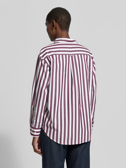 Frauenmodel trägt Relaxed Fit Langarmbluse aus reiner Baumwolle von GANT, weiß mit bordeauxroten Streifen, Ganzkörperansicht Rückansicht. Damen Langarmbluse von GANT.