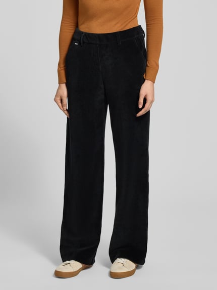Vrouwenmodel draagt zwarte Cordhose met elastische tailleband en steekzakken, model 'MAINE' van Brax, katoenmix, wijde pijpen. Close-up bovenlichaam.
