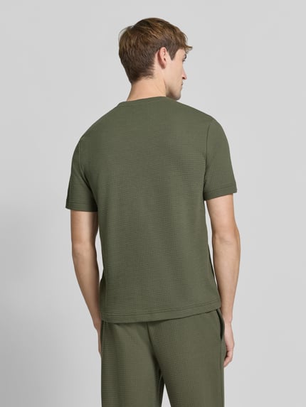 Männermodel trägt Regular Fit T-Shirt aus Baumwoll-Mix von HUGO in Olivgrün mit feiner Struktur, Ganzkörperansicht Rückansicht.