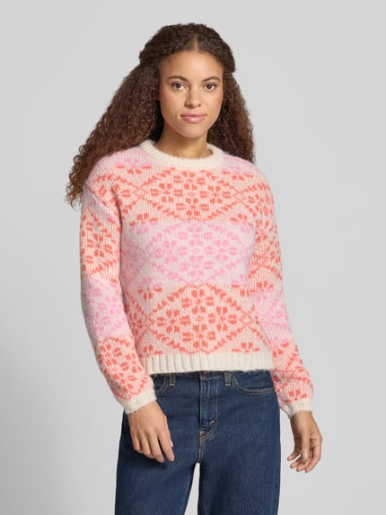 Frauenmodel trägt Pullover mit Jacquardstruktur Modell 'ONLCARO' von ONLY, mehrfarbiges geometrisches Allover-Muster, Rundhals, Strick, Nahaufnahme Oberkörper.