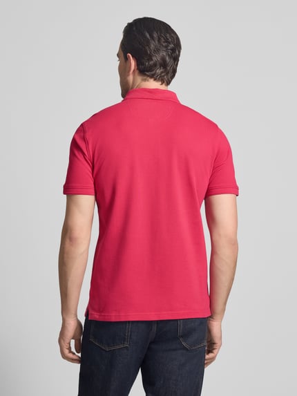 Männermodel trägt Slim Fit Poloshirt aus Baumwoll-Mix Modell 'Pete' von BRAX, rote Farbe, Rückenlänge 71 cm, Ganzkörperansicht Rückansicht.