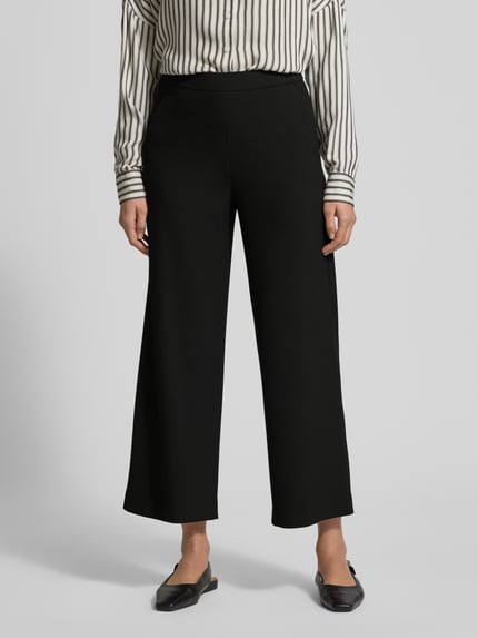 Frauenmodel trägt Wide Fit Schlupfhose mit Viskose-Anteil Modell 'Palina' von Raffaello Rossi in Schwarz mit Crêpe-Struktur, Ganzkörperansicht von vorne.