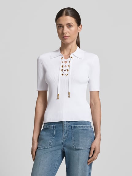 Vrouwenmodel draagt gebreid shirt met vetersluiting en platte kraag van MICHAEL Michael Kors, viscosemix met stretch, nauwsluitend model, V-hals met vetersluiting, fijnrib, labeldetails, voorkant volledig zichtbaar.