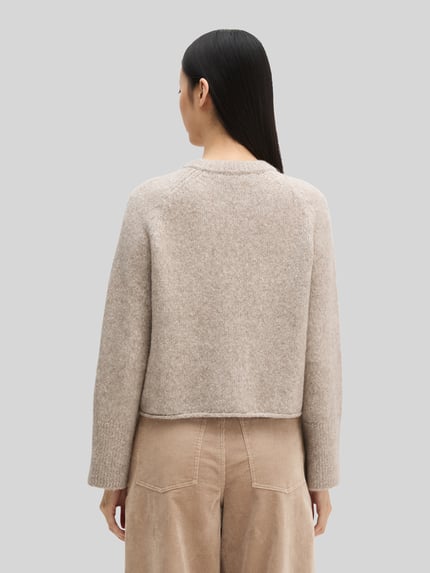 Frauenmodel trägt Strickjacke aus Alpaka Wolle mit Rollsaum von Marc O'Polo in Melange-Strickoptik, Struktur, Cropped-Länge, Rückansicht.