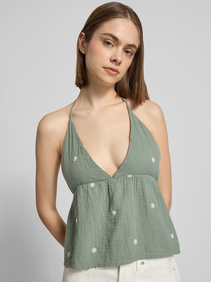 Kobiece modelka ma na sobie Crop Top aus reiner Baumwolle Modell 'THYRA RIO' od Only, efekt: jednolity kolor, krój regular fit, długość krótki, haft, dekolt w serek, ramiączka z wiązaniem na szyi, dekolt na plecach, czysta bawełna, zbliżenie na górną część ciała z przodu.