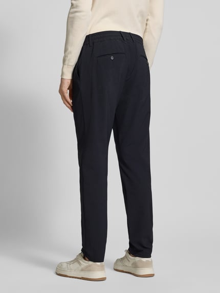 Männermodel trägt Slim Fit Stoffhose mit Strukturmuster von CRUNA in Dunkelblau, elastischer Material-Mix, Gesäßtaschen, elastischer Bund, Eingrifftaschen, Ganzkörperansicht Rückansicht.