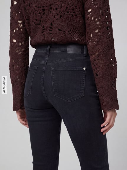 Frauenmodel trägt Slim Fit Jeans aus Baumwoll-Mix Modell 'PIPER SHORT' von CAMBIO, dunkles Jeansblau, strukturierte Oberfläche, Damen Slim Fit Jeans Kontext, Nahaufnahme Rückansicht, KI-modifiziertes Bild.