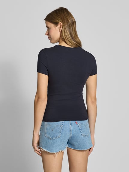 Modelka nosi damski t-shirt Slim Fit T-Shirt mit Logo-Stitching Modell 'Downtown' od REVIEW z mieszanki bawełny, wyhaftowane logo, okrągły dekolt, długość tyłu w rozmiarze S: 54 cm, ciemny granat, gładka tekstura, widok całej sylwetki z tyłu.
