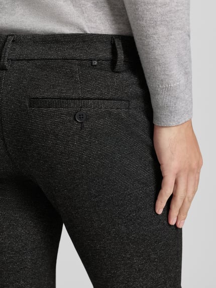 Männermodel draagt Slim Fit Chino met viscose-aandeel van Tom Tailor Denim, allover-motief, achterzak, detailopname rugzijde.