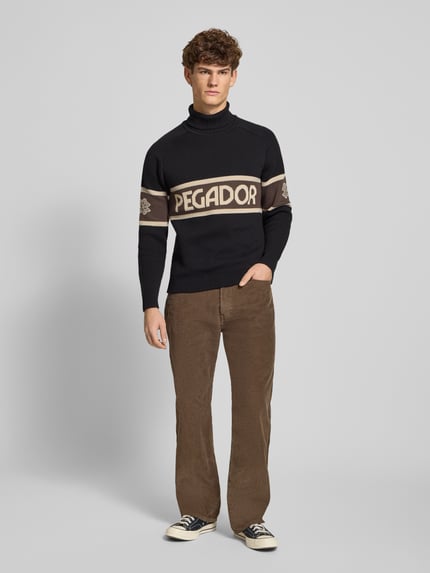 Mannelijk model draagt Strickpullover met Rollkragen van Pegador, zwart-beige, regular fit, katoenmix, label-print, voorkant volledig zicht.