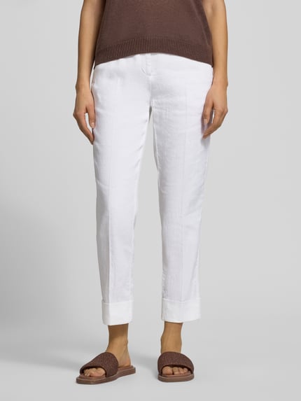 Vrouwenmodel draagt Leinenhose mit Baumwoll-Anteil van Cambio, wit, straight fit, steekzakken, riemlussen, enkellang, mix van katoen en linnen, model Krystal, knoop- en ritssluiting, omslag aan de pijpen, bandwijdte maat 36: 42 cm, binnenbeenlengte maat 36: 69 cm, close-up onderlichaam vooraanzicht.
