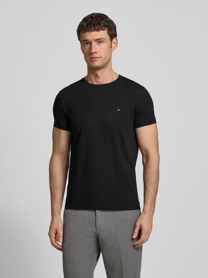 Männermodel trägt Slim Fit T-Shirt mit Rundhalsausschnitt von Tommy Hilfiger aus Baumwoll-Elasthan-Mix, Logo-Stickerei, Ganzkörperansicht von vorne.