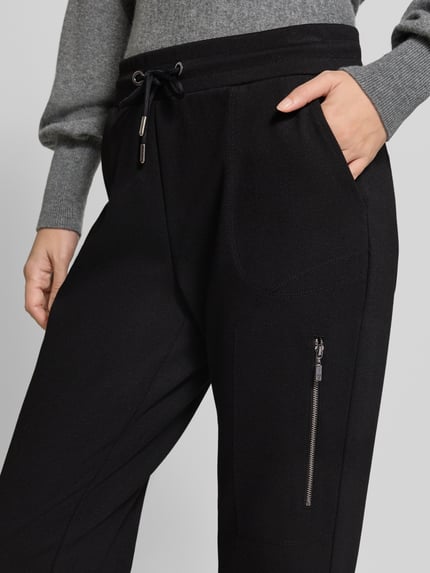 Frauenmodel trägt Slim Fit Sweatpants aus Viskose-Mix von monari in Schwarz, elastischer Bund mit Tunnelzug, Nahaufnahme Oberkörper.