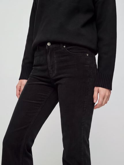Frauenmodel trägt Cordhose mit ausgestelltem Bein von Pepe Jeans in Schwarz, 5-Pocket-Design, Knopfverschluss, Nahaufnahme Oberkörper.