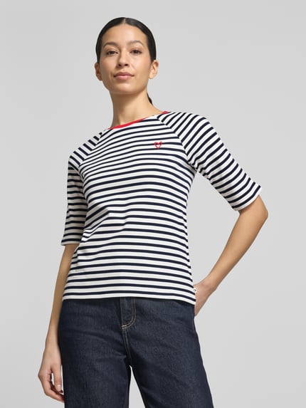 Frauenmodel trägt Shaped Fit T-Shirt aus reiner Baumwolle von Tom Tailor Denim, gestreift, unifarben, Herz-Stitching, Feinripp, Ganzkörperansicht von vorne.