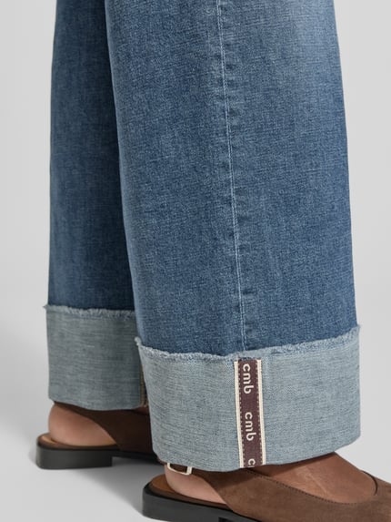 Frauenmodel trägt Wide Fit Jeans aus Baumwoll-Mix Modell 'ANTONIA' von CAMBIO, mittleres Blau, weite Beine, umgeschlagener Saum, Nahaufnahme Beinpartie, Damen Wide & Loose Fit Jeans von CAMBIO.