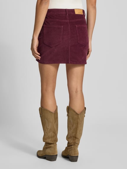 Vrouwenmodel draagt minirok uit katoenmix in corduroy look Model 'Yolanda' van NOISY MAY®, bordeaux, 5-pocketmodel, knoop- en ritssluiting, nauwsluitend, totale lengte maat S 41 cm, bandwijdte maat S 39 cm, geheel van achteren