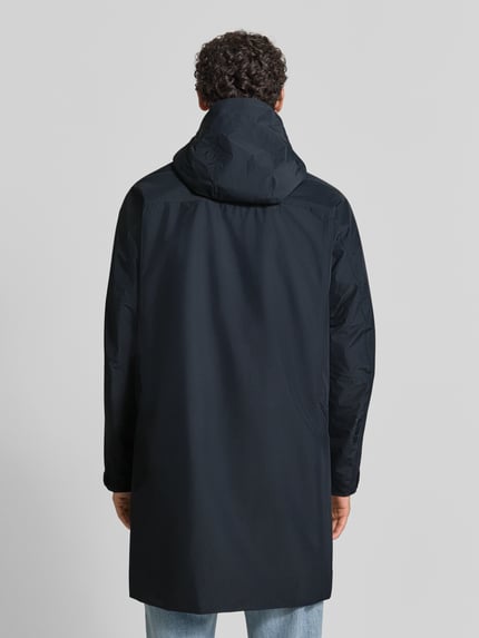 Męski model ma na sobie czarną parkę o kroju regular fit z kapturem, Peak Performance Regular Fit Parka mit Kapuze Modell 'Treeline HIPE', gładka tekstura, długość tyłu w rozmiarze M 99 cm, szerokość ramion w rozmiarze M 54 cm, szerokość klatki piersiowej w rozmiarze M 60 cm, długość rękawów w rozmiarze M 61 cm, widok całej sylwetki od tyłu.