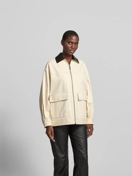 Frauenmodel trägt Relaxed Fit Jacke mit Umlegekragen von Anine Bing aus Reine Baumwolle, cremefarben mit Aufgesetzte Taschen und Reißverschluss, Rückenlänge 70 cm, Brustweite 59 cm, Ärmellänge 55 cm, Ganzkörperansicht von vorne.