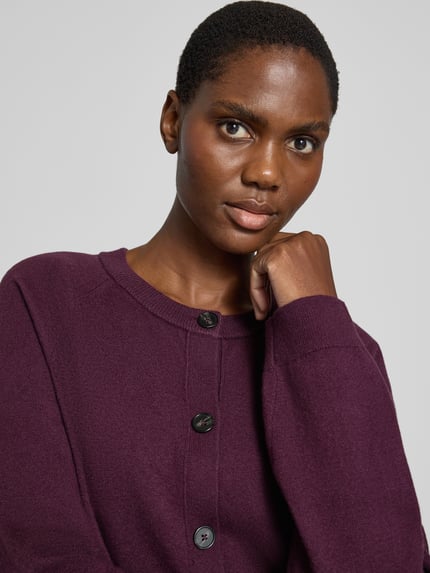 Frauenmodel trägt Regular Fit Strickjacke mit Raglanärmeln von MARC O’POLO, unifarben, Strickoptik, Nahaufnahme Oberkörper.