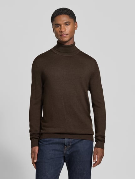 Männermodel trägt Wollpullover mit Rollkragen von Christian Berg Men in Dunkelbraun, gerader Schnitt, gerippte Abschlüsse, Ganzkörperansicht von vorne.