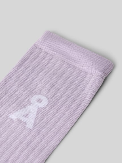 Produktfoto, Socken aus Baumwoll-Mix Modell 'SAAMUS' von ARMEDANGELS in hellem Flieder mit feinem Rippmuster, lila Hintergrund. Damen Socken von ARMEDANGELS.