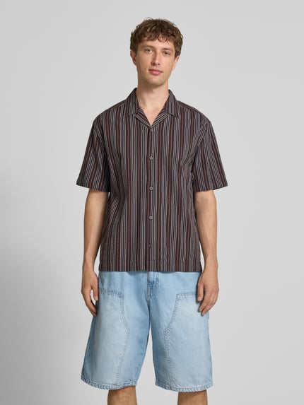 Männermodel trägt Relaxed Fit Freizeithemd aus reiner Baumwolle Modell 'CRUZ' von Only & Sons, gestreift, Resort-Kragen, Seersucker, Ganzkörperansicht von vorne.