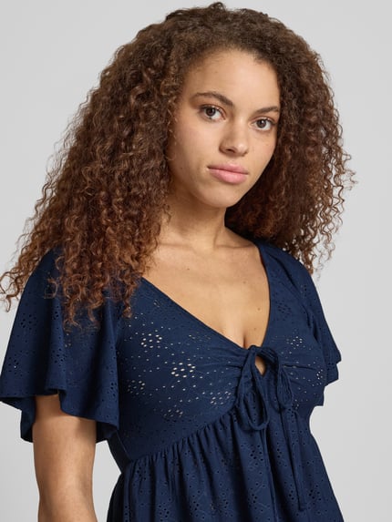 Frauenmodel trägt Slim Fit T-Shirt mit tiefem V-Ausschnitt Modell 'SMILLA' von Only, semitransparent, floral, Kurzarm, Stretch, Nahaufnahme Oberkörper.