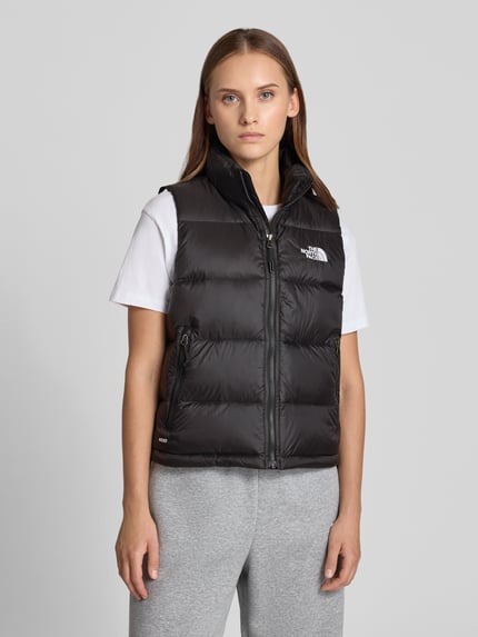 Frauenmodel trägt Steppweste mit Label-Stitching Modell 'HYDRENALITE DOWN A-LINE' von The North Face in Schwarz, glatte Textur, silberner Reißverschluss, Reißverschlusstaschen, Regular Fit, Stehkragen, Nahaufnahme Oberkörper.