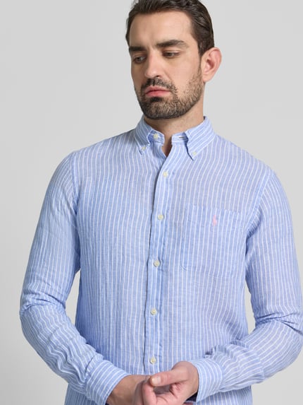 Männermodel trägt Regular Fit Freizeithemd aus reinem Leinen van Polo Ralph Lauren in blauw met witte strepen, borstzak, knoopsluiting, detailopname bovenlichaam.