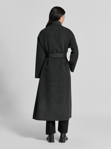 Frauenmodel trägt Mantel mit Schalkragen von Emporio Armani in Dunkelgrau, strukturierte Textur, doppelte Knopfleiste, Taillenband, taillierte Passform, Rückenlänge 129 cm, Schulterbreite 49 cm, Brustweite 53 cm, Ärmellänge 56 cm, Ganzkörperansicht Rückansicht.
