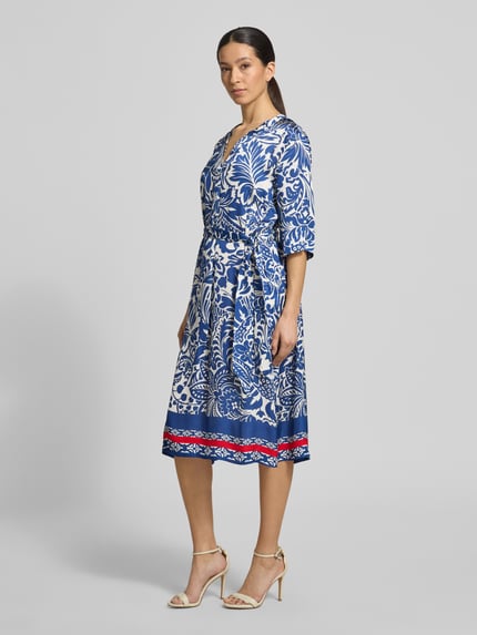 Frauenmodel trägt Tunikakleid aus Viskose mit Bindegürtel von WHITE LABEL, blauer Allover-Look, taillierter Schnitt, Midikleid, Ganzkörperansicht von vorne. Rückenlänge 113 cm, Brustweite 54 cm, Ärmellänge 36 cm.