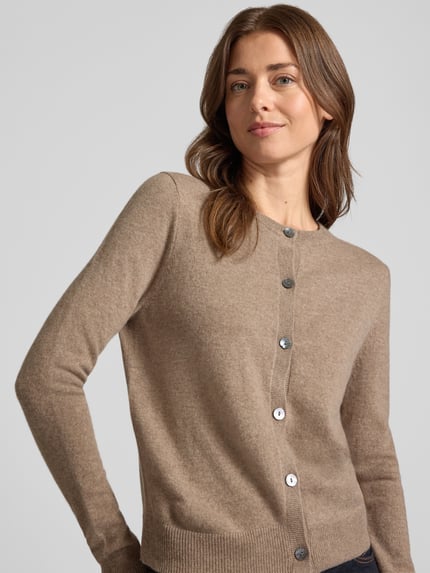 Frauenmodel trägt Strickjacke aus reinem Kaschmir mit durchgängiger Knopfleiste von Christian Berg Woman in Beige, Regular Fit, gerippte Abschlüsse, Nahaufnahme Oberkörper.