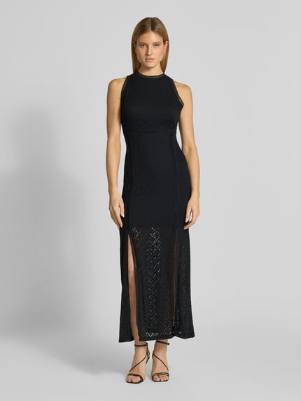 Frauenmodel trägt Maxikleid mit Spitze und Gehschlitz Modell 'NEW LIZA' von Guess im semitransparenten Material-Mix, körpernahes Design, Rundhalsausschnitt, Gehschlitz und Rückseitiges Label-Detail, Ganzkörperansicht von vorne.