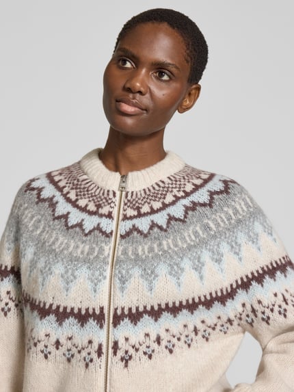 Frauenmodel trägt Regular Fit Strickjacke mit Allover-Muster von Closed, beige-braune und blaue Töne, elastischer Woll-Mix, Nahaufnahme Oberkörper.