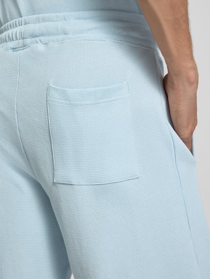 Mężczyznamodel nosi szorty z fakturowanym wzorem i wyhaftowanym logo 'Shorts mit Strukturmuster und Label-Stitching' od PROHIBITED, bawełna, krój regular fit, jasnoniebieski, elastyczny pas, Szerokość w rozmiarze M: 34 cm, Długość wewnętrzna nogawki w rozmiarze M: 25 cm, zdjęcie w detalicznym ujęciu tylnej części.