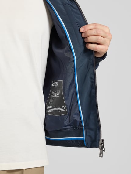 Mężczyznamodel nosi Regular Fit Jacke mit Kapuze od NAUTGÅRD, granatowa, dwukierunkowy zamek, elastyczne wykończenia, detal wnętrza, zbliżenie na górną część ciała.