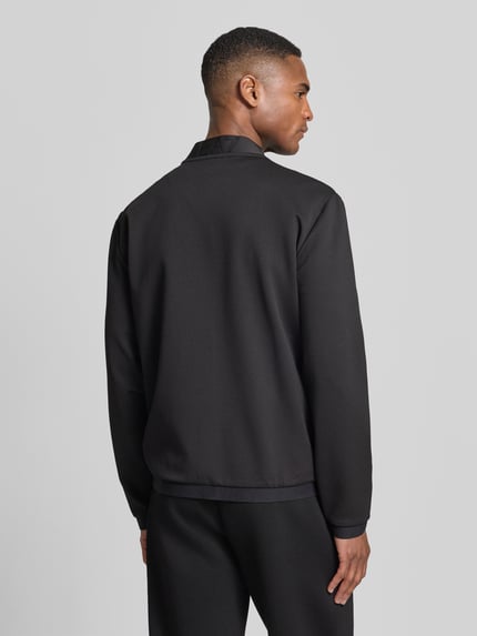 Männermodel trägt Sweatjacke mit Zweiwege-Reißverschluss von EA7 Emporio Armani, schwarz, Material-Mix mit Viskose-Anteil, Regular-Fit, Label-Patch, Reißverschlusstaschen, Rückenlänge 65 cm, Ärmel 65 cm, Ganzkörperansicht Rückansicht.