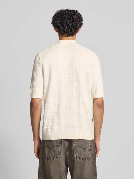 Männermodel trägt Regular Fit Poloshirt aus reiner Baumwolle Modell 'MENU' von Only & Sons in Creme mit Flechtoptik, Strukturmuster, Rippenabschlüssen, Polokragen und kurzem Reißverschluss, Strickmaterial, Ganzkörperansicht Rückansicht.
