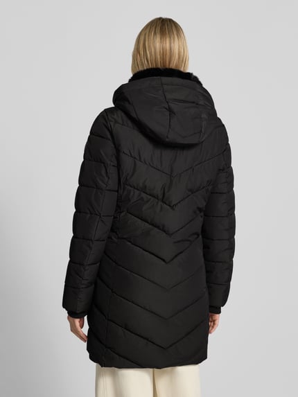 Frauenmodel trägt Jacke mit abnehmbarer Kapuze von NAUTGÅRD, schwarz, gesteppte Struktur, seitliche Reißverschlusstaschen, Ganzkörperansicht Rückansicht.