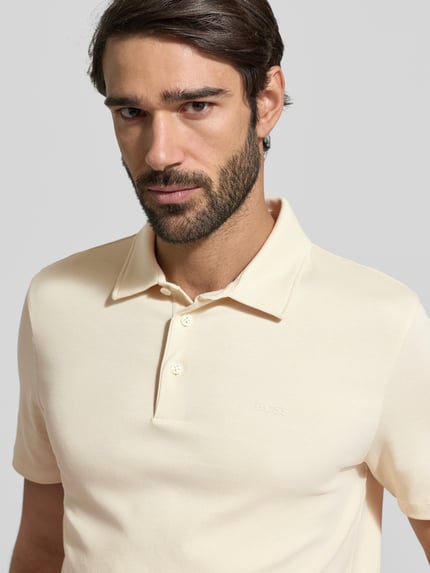 Mannelijk model draagt Regular Fit Poloshirt uit puur katoen Model 'PALOSH' van BOSS, look: effen, labelprint, polokraag, korte mouw, rompzoom met split, detailopname bovenlichaam.